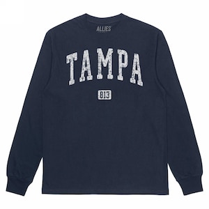 May include: Navy blue long-sleeve shirt with the word "TAMPA" in distressed white lettering across the chest, with "813" below. The word "ALLIES" is printed above the word "TAMPA".