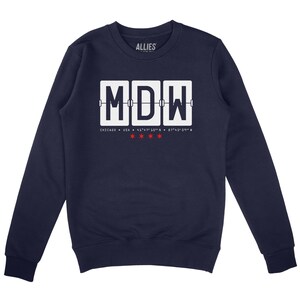 Puede incluir: Sudadera azul marino con un gráfico blanco de un tablero de salida de aeropuerto que muestra el código "MDW" para Chicago, Illinois. El texto "Chicago, USA" y las coordenadas están impresas debajo del tablero.