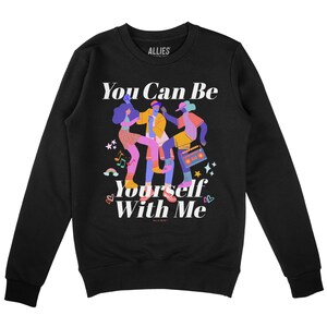 Op de afbeelding: Zwart sweatshirt met een afbeelding van drie dansende mensen en de tekst "You Can Be Yourself With Me" in wit.