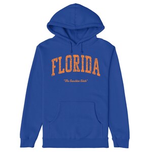 May include: A royal blue hoodie with a distressed orange graphic that says "FLORIDA" and "The Sunshine State".