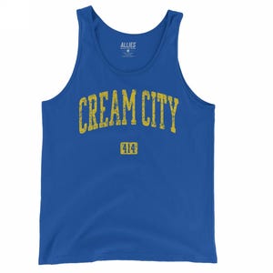 May include: A royal blue vest top featuring the text "CREAM CITY" in distressed yellow lettering. Below the text is the number "414" in a yellow rectangle. The vest top is a casual style.