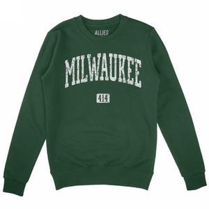 May include: A dark green sweatshirt featuring the word "MILWAUKEE" in distressed white lettering, and the number "414" underneath. The brand name "ALLIES" is printed above the word "MILWAUKEE".