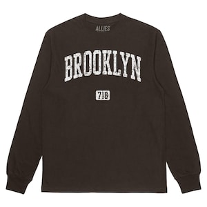 May include: Black long-sleeved t-shirt with a white distressed graphic that says "BROOKLYN" and "718" in a vintage style.