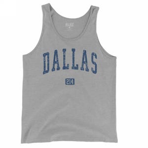 May include: A gray tank top with the word "DALLAS" in distressed blue lettering across the chest. Below the word "DALLAS" is the number "214" in a blue rectangle. The tank top is sleeveless and made of a soft material.