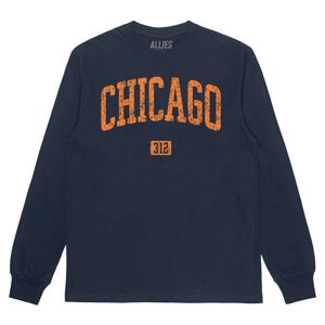 Puede incluir: Camiseta de manga larga azul marino con un gráfico naranja de estilo vintage que dice "CHICAGO" y "312".
