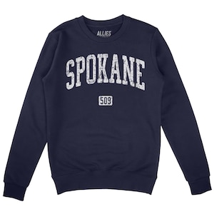 May include: Navy blue sweatshirt with a white distressed graphic that says "SPOKANE" with the number "509" underneath. The sweatshirt is a crew neck style.