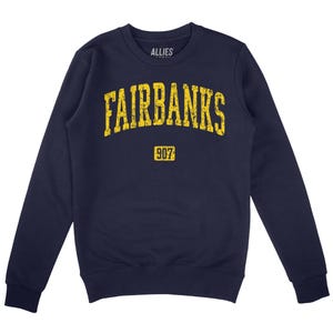 May include: Navy blue sweatshirt with a yellow arch design that reads "FAIRBANKS" and "907" in a vintage style.
