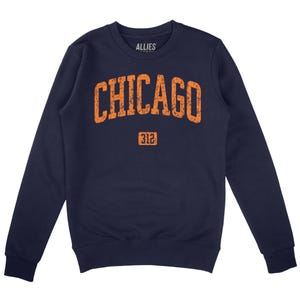 Puede incluir: Sudadera azul marino con un estampado gráfico naranja de "CHICAGO" en una fuente de estilo universitario vintage con el número "312" debajo. El nombre de la marca "ALLIES" está impreso en la etiqueta interior del cuello.