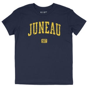 May include: A navy blue t-shirt with a yellow distressed graphic that says "JUNEAU" with the number "907" underneath.