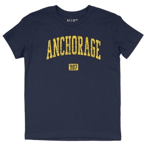 May include: Navy blue t-shirt with a yellow distressed graphic that says "ANCHORAGE 907".