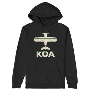 May include: Black hoodie featuring a white airplane graphic and the text "KOA" in white with green accents.