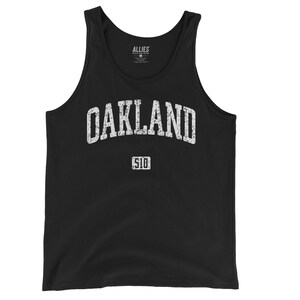 May include: Black tank top with a white distressed graphic that says "OAKLAND" with "510" underneath.