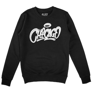 May include: Black sweatshirt with a white graphic print of the word "CHICAGO" in a graffiti style with a halo above the word.