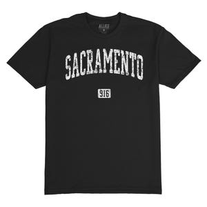 Puede incluir: Camiseta negra con la palabra "SACRAMENTO" en letras blancas desgastadas en el pecho. Debajo, el número "916" en un recuadro blanco. La camiseta tiene cuello redondo y mangas cortas.