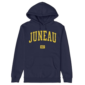 May include: Navy blue hoodie with a yellow distressed print of "JUNEAU" and "907" on the front.