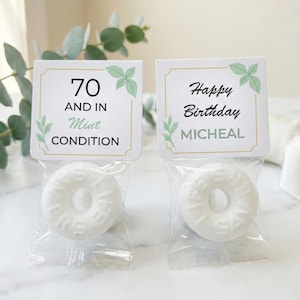 May include: Two small clear cellophane bags each containing a white mint candy. Each bag has a white card with text and green leaf illustrations. One card reads "70 and in Mint Condition", the other reads "Happy Birthday Micheal".
