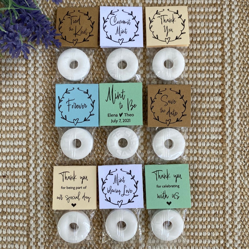 Puede incluir: Surtido de bolsas de regalo de boda con mentas blancas y tarjetas impresas. Las tarjetas tienen diferentes mensajes, que incluyen "Tied the Knot", "Commit Mint", "Thank You", "Forever", "Mint to Be", "Save the Date", "Thank you for being part of our special day", "Mint to be loving Love" y "Thank you for celebrating with us".