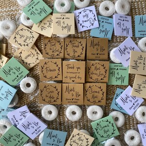 Puede incluir: Surtido de peque&ntilde;as mentas redondas blancas envueltas en bolsas de pl&aacute;stico transparentes con etiquetas de papel marr&oacute;n, verde y azul. Las etiquetas tienen varios textos, incluyendo "Mint to Be", "Save the Date", "Thank You" y "Commit Mint".
