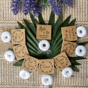 Puede incluir: Cajas de regalo marrones con mentas blancas y varios mensajes con tem&aacute;tica de boda, que incluyen "Save the Date", "Thank You", "Tied the Knot", "Forever", "Mint to Be", "Commit Mint" y "Mint blowing Love".