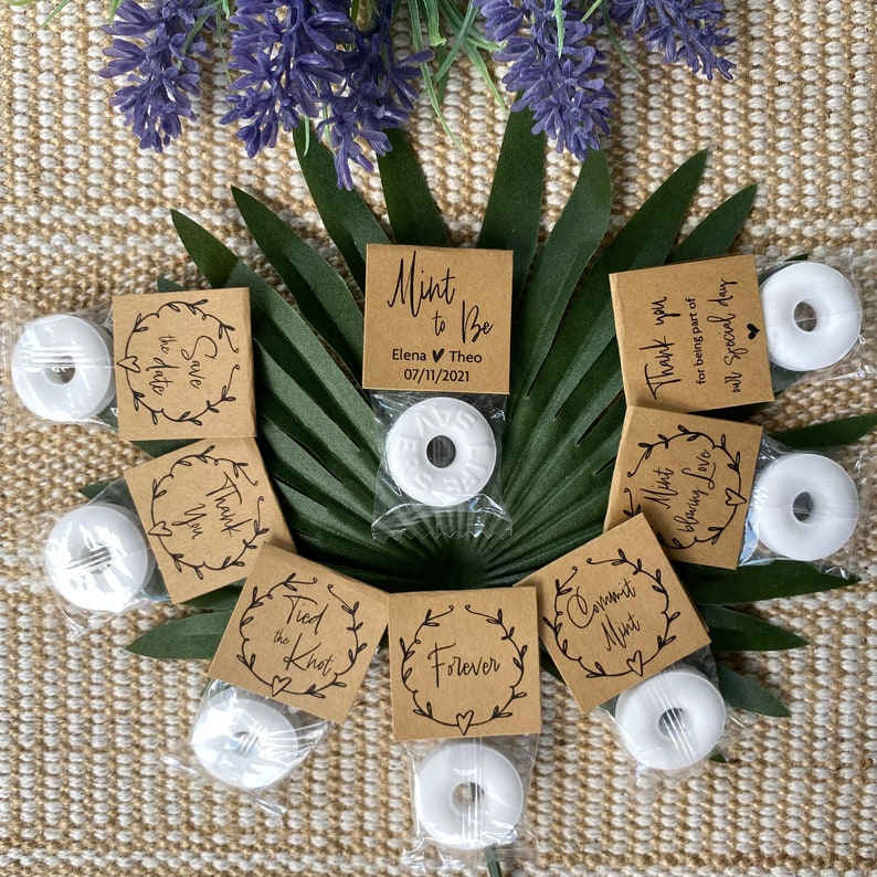 Puede incluir: Cajas de regalo marrones con mentas blancas y varios mensajes con tem&aacute;tica de boda, que incluyen "Save the Date", "Thank You", "Tied the Knot", "Forever", "Mint to Be", "Commit Mint" y "Mint blowing Love".