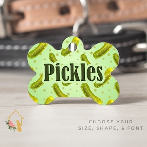 May include: Green bone-shaped dog tag with a white background and a repeating pattern of green pickles. The tag has the word "Pickles" printed in black.