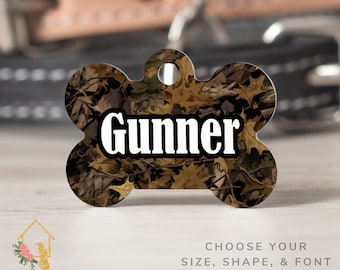May include: A brown and tan camouflage dog tag in the shape of a bone with the name "Gunner" printed in white.