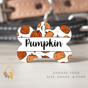 May include: White bone-shaped dog tag with an orange and white pumpkin pattern and the word "Pumpkin" in black text.