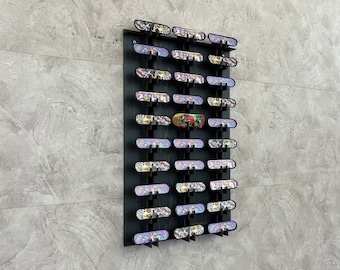 May include: A black wall-mounted display rack with multiple slots for holding fingerboards. The rack is filled with fingerboards of various colors and designs. The fingerboards are arranged in rows and columns.