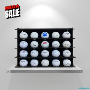 May include: A black shelf unit with 18 golf balls displayed on three shelves. The golf balls are white with various logos and numbers printed on them.