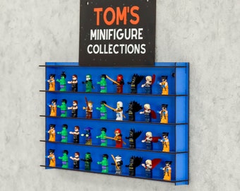 Può includere: Un ripiano a muro blu con quattro livelli per esporre minifigure. Il ripiano ha una cornice nera e un cartello che recita "TOM'S MINIFIGURE COLLECTIONS".