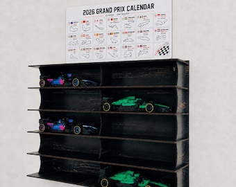 Könnte beinhalten: Ein schwarzes Wandregal aus Holz mit fünf Ebenen, das vier Spielzeug-Rennwagen enthält. Über dem Regal befindet sich ein weißes Schild mit der Aufschrift 2026 GRAND PRIX CALENDAR und einem Raster aus 23 Rennstrecken und Renndaten.