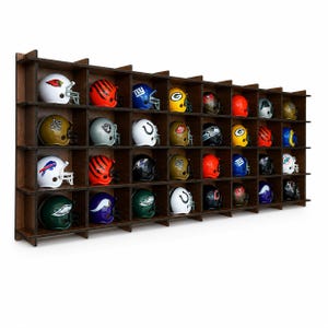May include: A dark brown wooden display shelf with a grid of thirty-two square compartments, each containing a miniature American football helmet representing various professional teams with distinct colours, logos, and face masks arranged in rows.