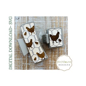 May include: Two hair clips with a brown chicken and chick design on a white background with a wire fence pattern. The text "BirchBound DESIGNS" is visible in the lower right corner of the image.