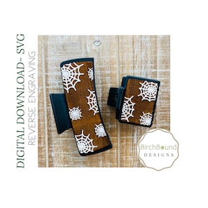 May include: Two black hair clips with a brown wood-like surface and white spiderweb designs. The text "BirchBound DESIGNS" is visible in the image.