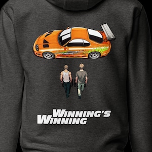May include: Dark gray hoodie featuring an orange sports car graphic with a spoiler and two figures walking below. The text "Winning's Winning" is printed in white at the bottom of the design.