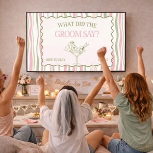Può includere: Un gruppo di donne festeggia davanti a uno schermo televisivo che mostra un gioco intitolato "What Did The Groom Say?". Lo schermo presenta un'illustrazione di sposa in un bicchiere da Martini. La stanza è decorata con fiori e candele.