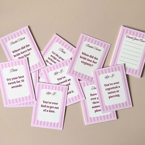 Pode incluir: Cart&otilde;es de trivia de casamento listrados em rosa e branco com v&aacute;rias perguntas e desafios. Os cart&otilde;es incluem perguntas como "Onde a noiva deu o seu primeiro beijo?" e "Tente o seu melhor twerk por 10 segundos."