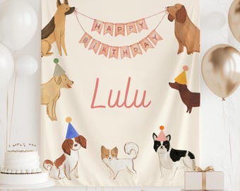 May include: A beige backdrop with a pink banner that reads "Happy Birthday".  The backdrop features illustrations of dogs wearing party hats. The name "Lulu" is written in pink cursive.