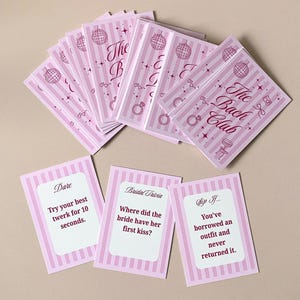 Pode incluir: Cart&otilde;es listrados em rosa e branco com o texto "The Bach Club" e ilustra&ccedil;&otilde;es tem&aacute;ticas de casamento. Tr&ecirc;s cart&otilde;es individuais com perguntas e desafios tamb&eacute;m s&atilde;o vis&iacute;veis. Ideal para uma despedida de solteira.