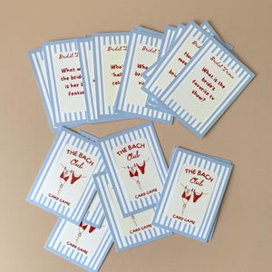 May include: A selection of blue and white striped cards. Some cards are labelled "Bridal Trivia" with questions. Others say "The Bach Club" with a graphic of red lingerie. The words "Card Game" are also visible on the cards.