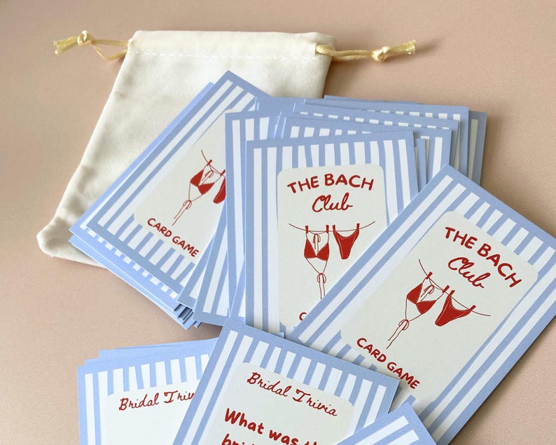 May include: A collection of bridal trivia cards featuring blue and white striped borders and red bikini illustrations. The cards are labelled "THE BACH Club" and "CARD GAME". A small drawstring bag is also included.