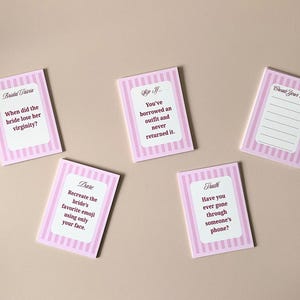 Pode incluir: Cart&otilde;es rosa e brancos listrados para um jogo de ch&aacute; de panela. Os cart&otilde;es apresentam perguntas e desafios, como "Quando a noiva perdeu a virgindade?" e "Crie o seu pr&oacute;prio".