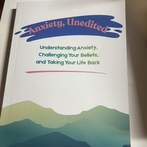 May include: A softcover book titled Anxiety, Unedited: Understanding Anxiety, Challenging Your Beliefs, and Taking Your Life Back by Kasey Magnuson, MA, LLP. The white cover features a blue brushstroke graphic and a green mountain landscape.