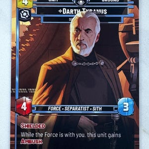May include: A collectible card featuring Darth Tyranus. The card has a portrait of the character, with text including "FORCE SEPARATIST SITH" and "AMBUSH". The card has a gold, red, and blue color scheme.