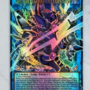 May include: A Yu-Gi-Oh! trading card featuring a dark cyberse monster with gold and pink accents. The card is titled "Decode Talker Integration" and includes game text. The card has a blue and black background with a holographic effect.
