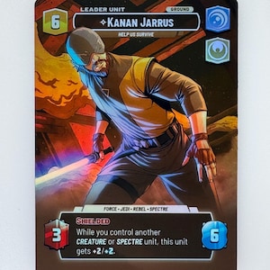 Puede incluir: Una tarjeta coleccionable de Star Wars con Kanan Jarrus. La tarjeta tiene un fondo marrón con una ilustración del personaje en amarillo, negro y azul. El texto incluye "Leader Unit", "Help Us Survive" y "Shielded".