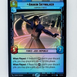 Può includere: Carta collezionabile di Anakin Skywalker. La carta presenta un'illustrazione del personaggio in una posa dinamica, con una combinazione di colori blu e nero. Il testo include "Champion of Mortis", "Force Jedi Republic" e le istruzioni di gioco. La carta ha un valore unità di 6 e un valore terreno di 7.