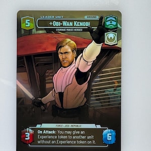 May include: A Star Wars trading card featuring Obi-Wan Kenobi. The card shows a character illustration with the text "Obi-Wan Kenobi" and "Courage Makes Heroes". The card has a 5-point value and includes game instructions.