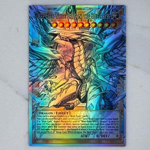 May include: A holographic trading card featuring a dragon with the text "Deep-Eyes White Dragon, The Blue Abyss". The card has a blue, white, and gold color scheme with detailed artwork of the dragon. The card also has text describing its effects.