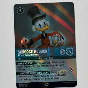 May include: Scrooge McDuck trading card from the Disney Lorcana trading card game. The card features a colorful illustration of Scrooge McDuck, the richest duck in the world. The card text reads "I'm Going Home! During your turn, this character gains Evasive. (They can challenge characters with Evasive.) I Didn't Get Rich By Being Stupid During your turn, whenever this character banishes another character in a challenge, you may play an item for free."